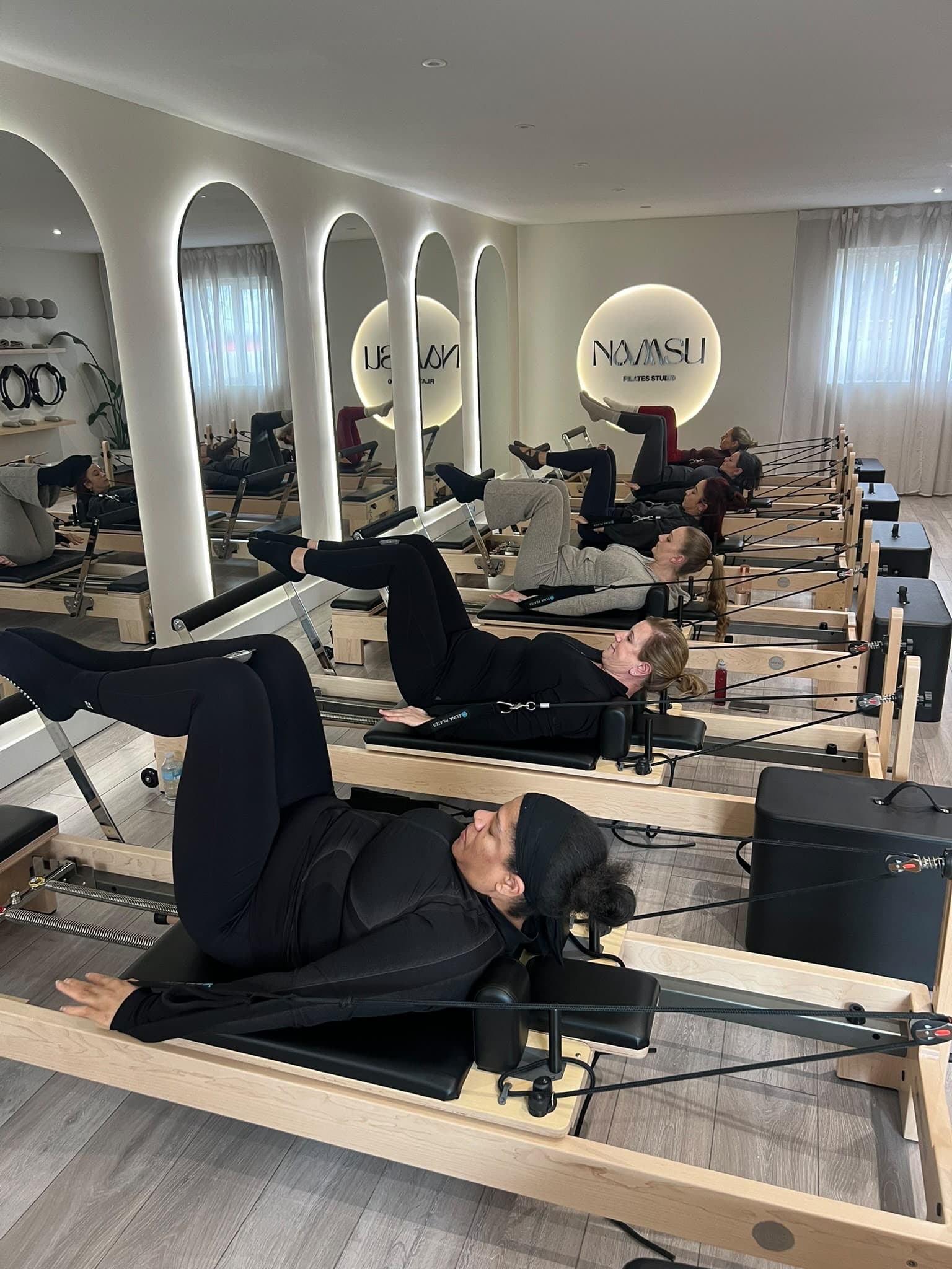 A reformer class lying back on the carriages with legs extended in the foot straps